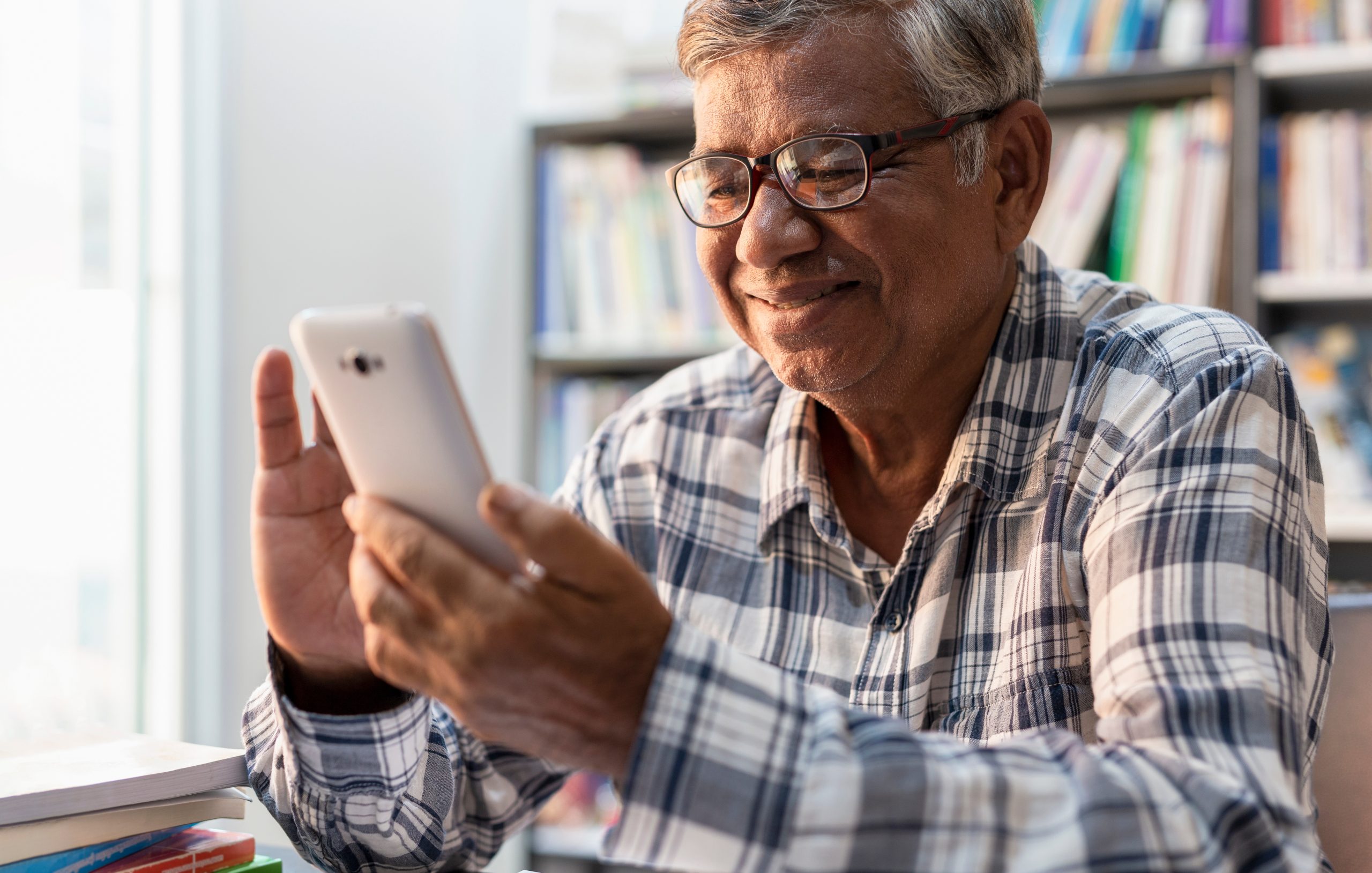 Happy elderly Asian reviewing Medicaid ride on his phone